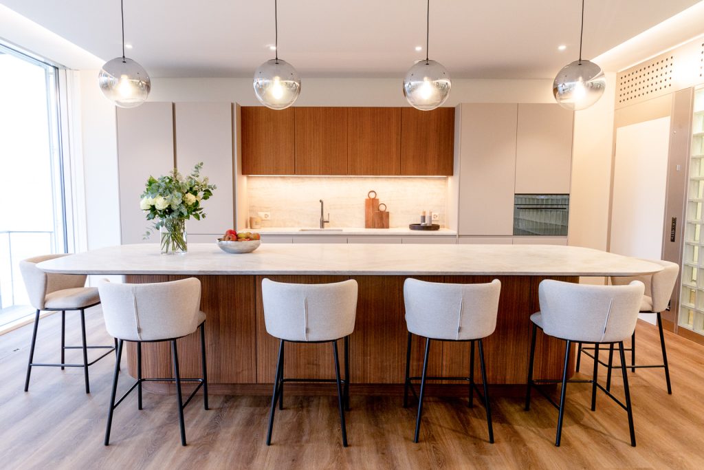 Modern kitchen with large island, wooden cabinetry, upholstered bar