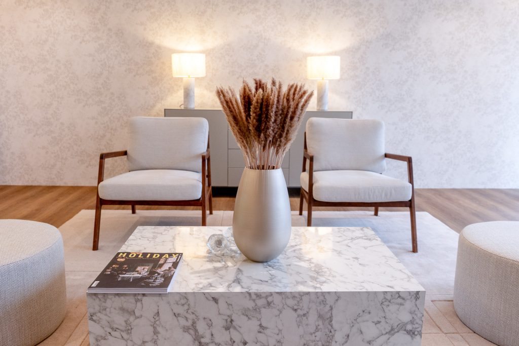 Modern living room seating area with armchairs, marble coffee table and neutral decor